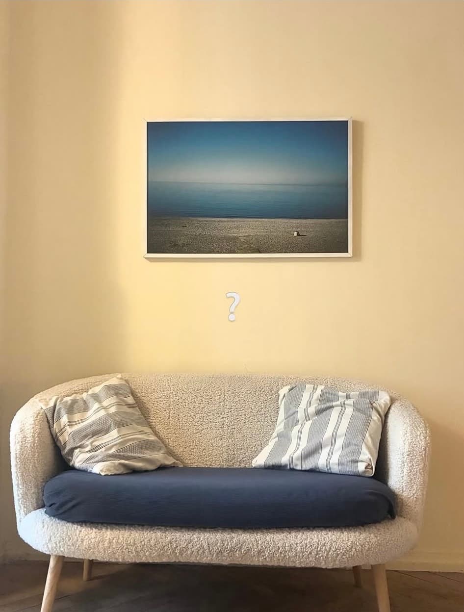 The therapy room: a white sofa with striped cushions beneath a framed seascape