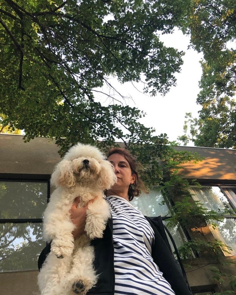 Tako holding her white poodle outside, under the trees